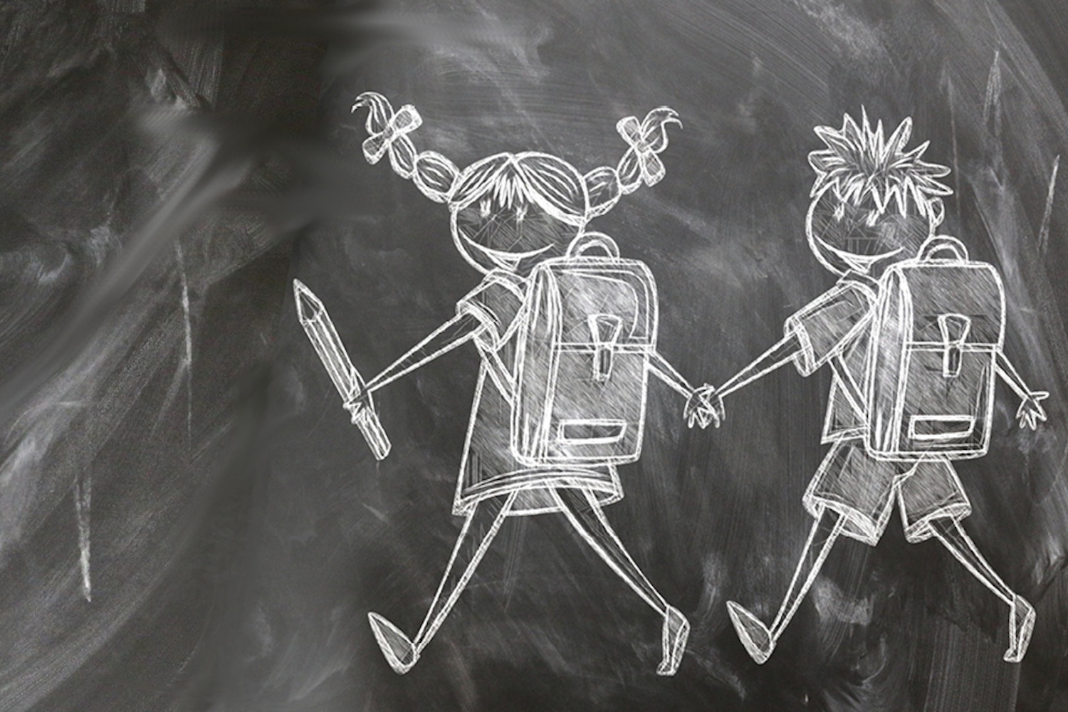 Das Bild zeigt ein Mädchen und einen Jungen mit Schultaschen und Stift als Kreidezeichnung auf einer Schultafel